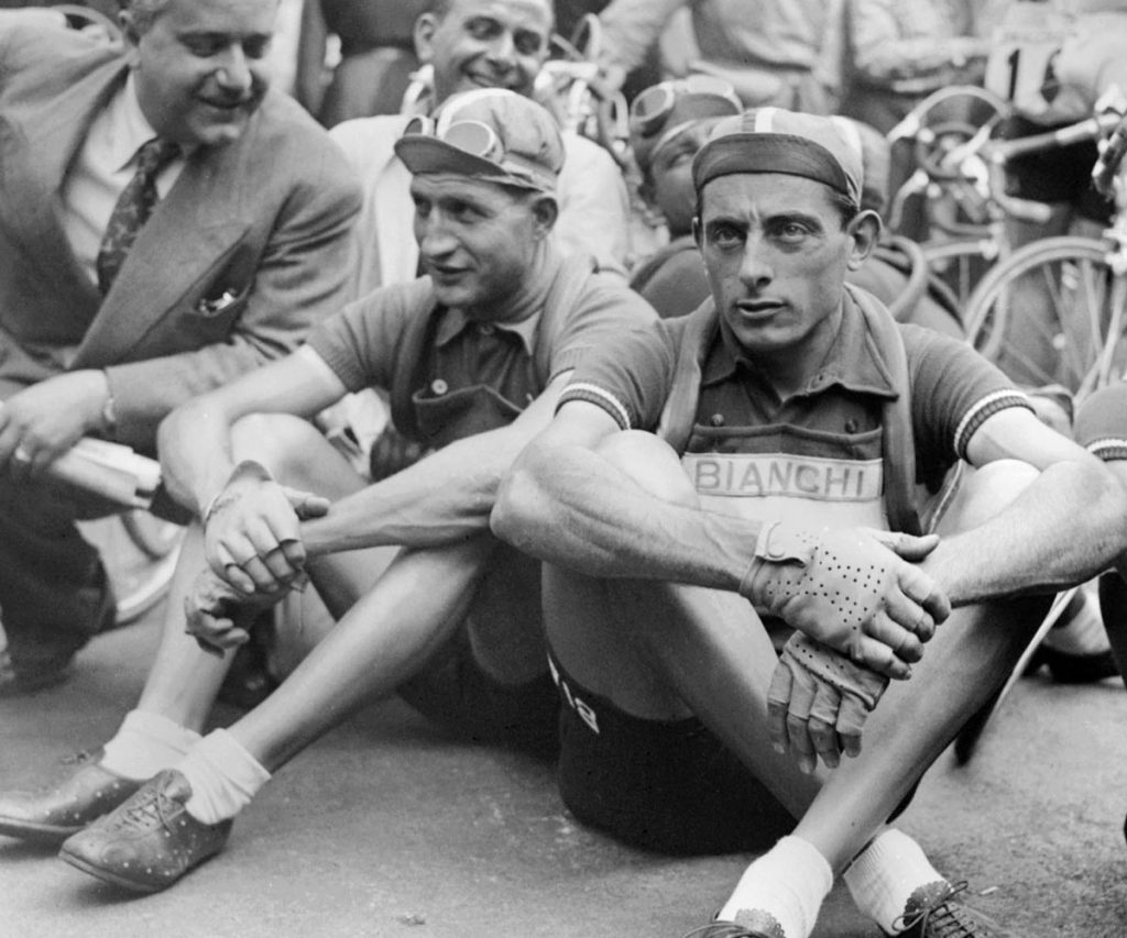 Fausto Coppi e Gino Bartali seduti a terra durante una pausa al Tour de France negli anni ’50